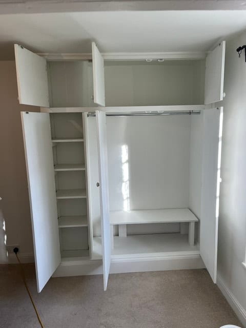 Built-in white wardrobe with open doors showing shelving and desk space